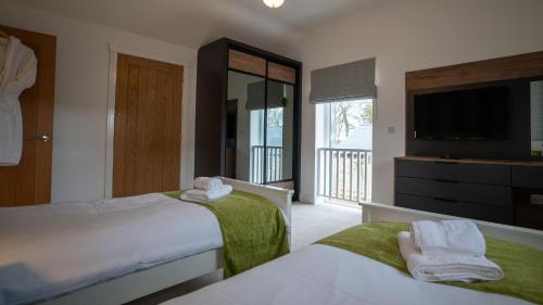 ein Schlafzimmer mit zwei Betten und einem Flachbildfernseher in der Unterkunft Northumberland Luxury Stays - The Galloway in West Chevington