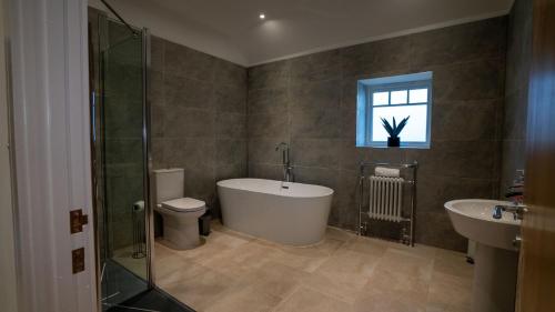 ein Badezimmer mit Badewanne und Toilette und einem Fenster in der Unterkunft Northumberland Luxury Stays - The Galloway in West Chevington