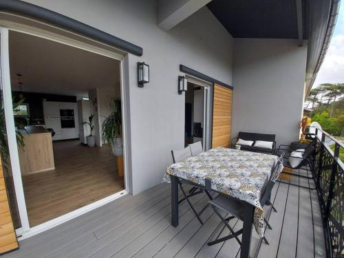 una mesa y sillas en un porche con balcón en Magnificent accommodation , 200m from the beach., en Labenne