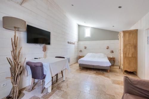 a bedroom with a bed and a table and a tv at Maison pour 10, accès direct à la plage in Ars-en-Ré