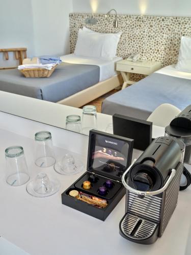a room with two beds and a table with a phone and glasses at Kanale's Rooms & Suites in Naousa