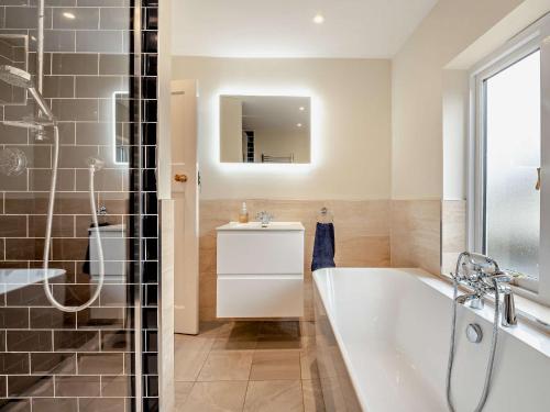 een badkamer met een bad, een wastafel en een spiegel bij 3 Bed in Broughton 94143 in Broughton