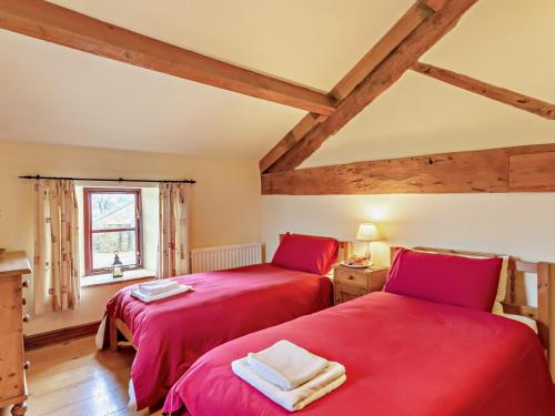 two red beds in a room with wooden ceilings at 3 Bed in Malham 94260 in Airton