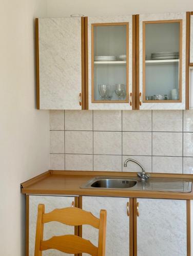 a kitchen counter with a sink and a wooden chair at Apartments Mustel Drage - Adults Only in Drage