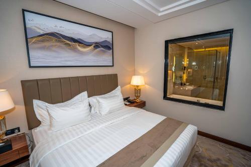 um quarto com uma cama grande e almofadas brancas em Le Bosquet em Shaqra