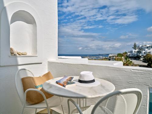 a white table and chairs with a hat on a balcony at Kanale's Rooms & Suites in Naousa