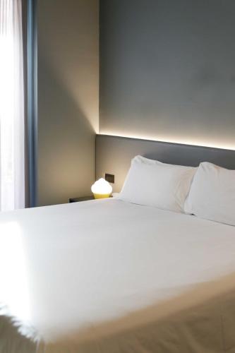 a bed with white sheets and pillows in a room at Arryvo Hotel in Lecce