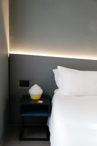 a bed with a side table with a yellow bowl on it at Arryvo Hotel in Lecce