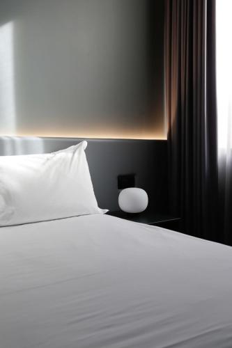 a bed with a white pillow and a window at Arryvo Hotel in Lecce