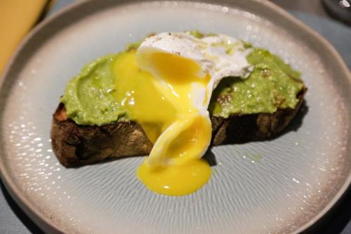 a white plate with an egg on a piece of food at Arryvo Hotel in Lecce