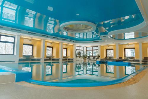 ein großer Pool in einem Gebäude mit blauer Decke in der Unterkunft Sporthotel am Semmering in Semmering