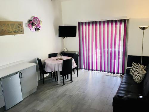 - un salon avec une table et un rideau rose dans l'établissement Maison de vacances St Cyprien Plage, à Saint-Cyprien