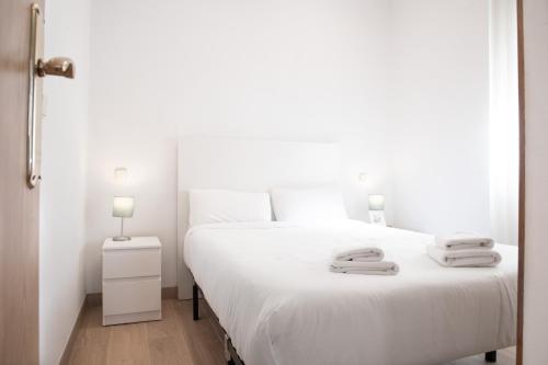 a bedroom with a white bed with two towels on it at Renovado apartamento a 10 min del Aeropuerto y a 3 min de IFEMA in Madrid