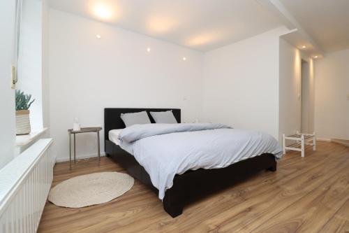 a white bedroom with a large bed and wooden floors at Louisappart - Eupen Zentrum in Eupen