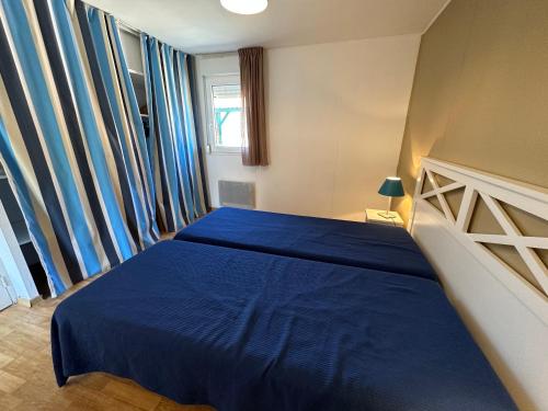 a bedroom with a blue bed and a window at Résidence Mes Amours d'Enfants - Les Villas du Lac in Soustons