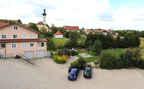 zwei Autos auf einem Parkplatz neben einem Haus geparkt in der Unterkunft Ferienwohnung Zehmerhof in Walpertskirchen