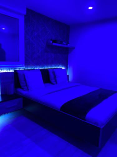a blue bedroom with a large bed with blue lighting at Atelier chaleureux - CDG in Tremblay-En-France