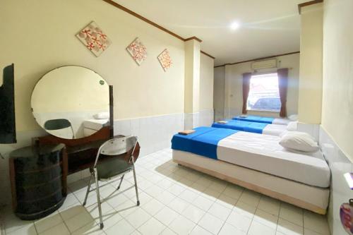 a bedroom with a bed and a mirror and a chair at Wisma Sodikin Mitra RedDoorz in Palembang