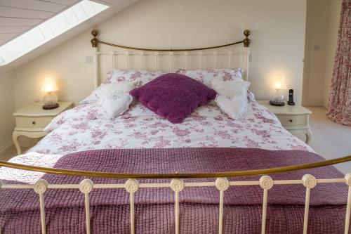 a bed with a purple comforter and pillows on it at Doleen House in Ballyconneely