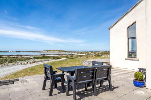 a table and chairs on a patio with a view of the ocean at Doleen House in Ballyconneely