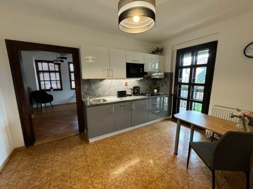 uma cozinha com armários brancos, uma mesa e uma sala de jantar em Kutna Hora perfect apartment em Kutná Hora