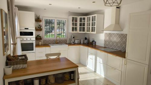 a kitchen with white cabinets and a wooden counter top at Lou Masadous : Magnifique villa tout confort avec piscine chauffée 11x3.5 in Montauroux