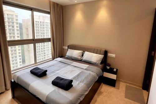 Prime 1 BHK in Hiranandani Powai في مومباي: غرفة نوم بسرير كبير عليها وسادتين