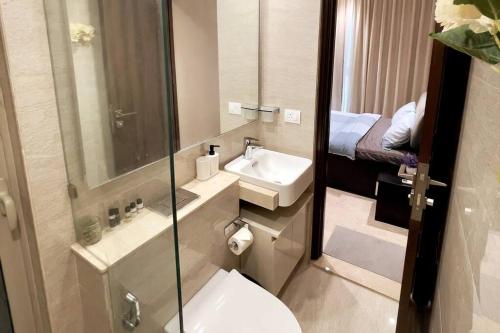 a bathroom with a toilet and a sink and a bed at Prime 1 BHK in Hiranandani Powai in Mumbai