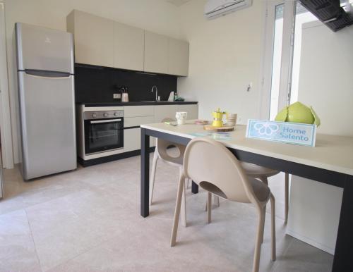 a kitchen with a table and chairs and a refrigerator at Azzurro Mare Aparthotel in Torre Mozza
