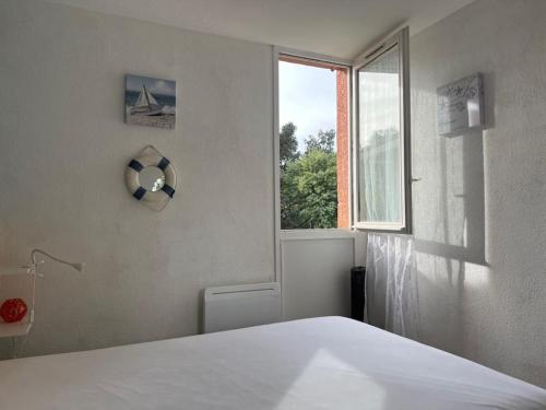 une chambre avec un lit blanc et une fenêtre dans l'établissement CAVALIERE LE LAVANDOU Au Chêne Liège, au Lavandou