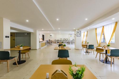 昆明市にあるCity Comfort Inn Kunming Dashuying Yejin Hospital Wangdaqiaoのテーブルと椅子、カフェテリアが備わる広い客室です。