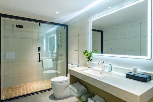 ein Badezimmer mit einem Waschbecken, einem WC und einem Spiegel in der Unterkunft City Comfort Inn Kunming Dashuying Yejin Hospital Wangdaqiao in Kunming