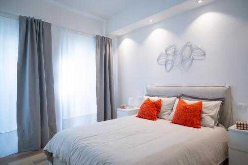- une chambre avec un grand lit blanc et des oreillers orange dans l'établissement Maison BP - A 2 minuti dalla Stazione Ferroviaria, à Prato