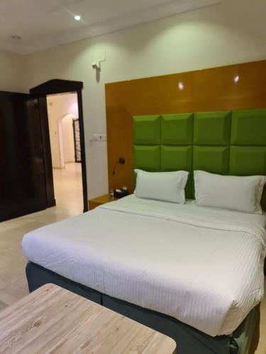 a bedroom with a large bed with a green headboard at شاليهات دشيل لبيوت العطلات الاقتصادية in Taif