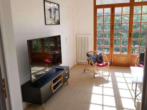 a living room with a flat screen tv in a room at Maison au calme avec jardin à 5 min de Tournus in Cuisery