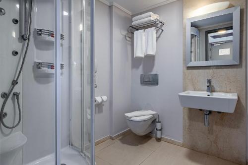 uma casa de banho com um chuveiro, um WC e um lavatório. em Sisus Marina Hotel em Cesme