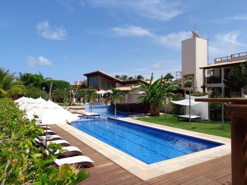 a swimming pool with lounge chairs next to a building at Apartamento A-11 Pipa Beleza Resort in Pipa