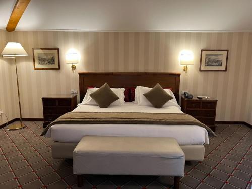 una camera d'albergo con un grande letto e due lampade di Hotel De La Paix a Lugano