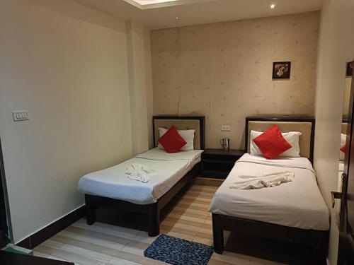 HOTEL SERENE في شيلونغ: سريرين في غرفة صغيرة مع وسائد حمراء