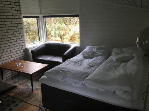 a bed in a room with a chair and a table at Harvey`s Bed & Breakfast in Hjørring
