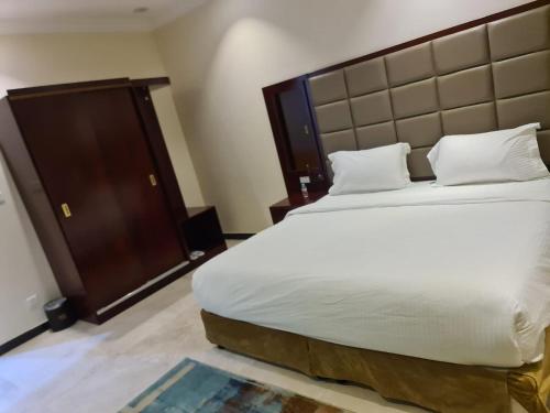 a bedroom with a large white bed with a large headboard at شاليهات دشيل لبيوت العطلات الاقتصادية in Taif