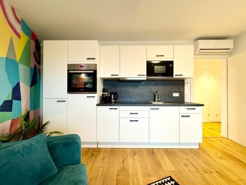 eine Küche mit weißen Schränken und einem Sofa in einem Zimmer in der Unterkunft Kreative Wohnung mit Balkon in Wien