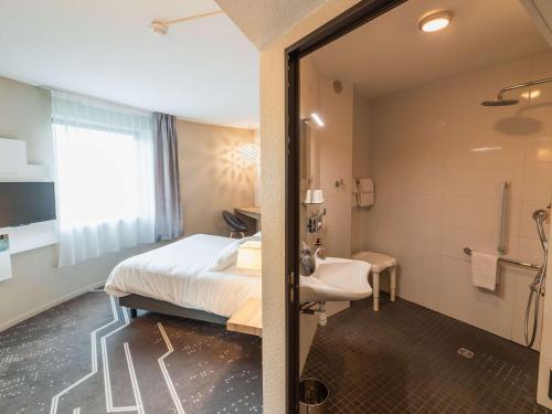 a hotel room with a bed and a bathroom at Mercure Poitiers Site du Futuroscope in Chasseneuil-du-Poitou