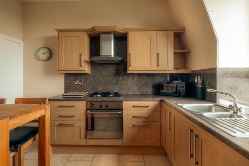 una cucina con armadi in legno e lavandino di Fonthill Residence - SJA Stays - 1 Bed Apartment ad Aberdeen