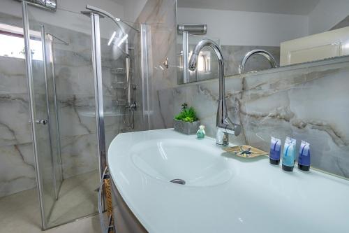 een badkamer met een witte wastafel en een douche bij וילה ריש - מושלמת למשפחות עם בריכה, ג'קוזי ונוף in Yarka