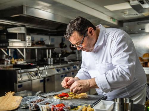 Een man in een keuken die eten klaarmaakt. bij Novotel Monte-Carlo in Monte Carlo