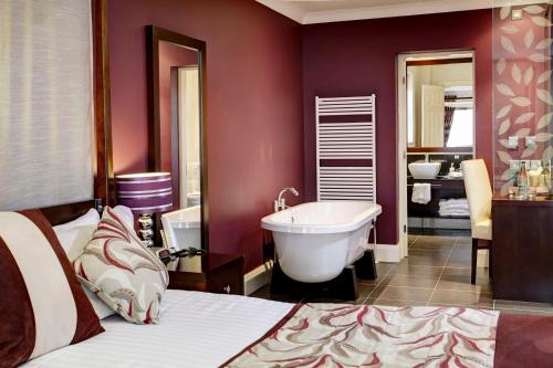 Best Western Forest and Vale Hotel في بيكرينغ: غرفة نوم بسرير وحوض استحمام وحمام