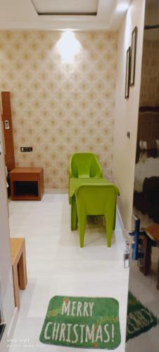 Varanasi Villa(B&B) في فاراناسي: غرفة بها كرسي أخضر وسجادة عيد ميلاد سعيدة