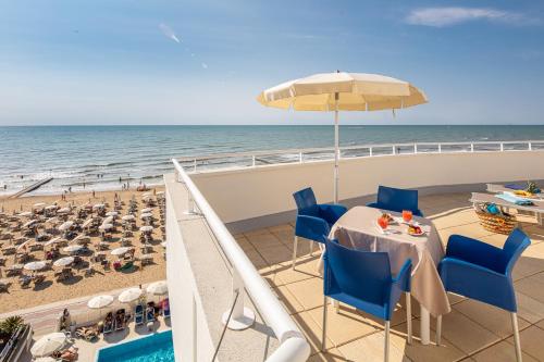 een balkon met een tafel en stoelen en het strand bij Hotel Condor in Lido di Jesolo