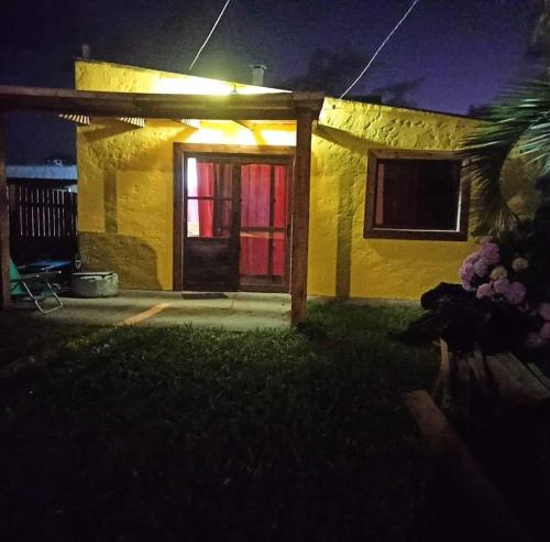 una casa amarilla con una puerta roja por la noche en LO de Yamaha, en Rocha